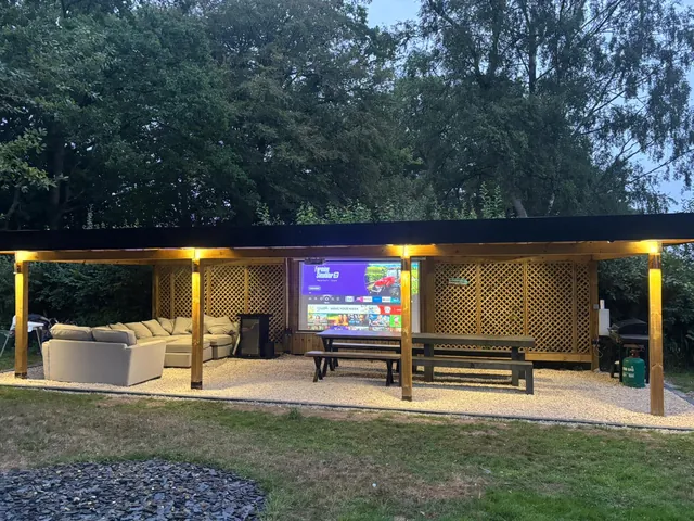 Garden room with seating, a dining table and lighting under a timber roof