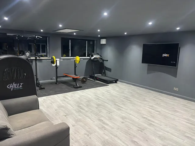 Home gym with grey walls, downlights and exercise equipment