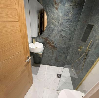 Shower room finished in marbled stone tiling with brass fittings
